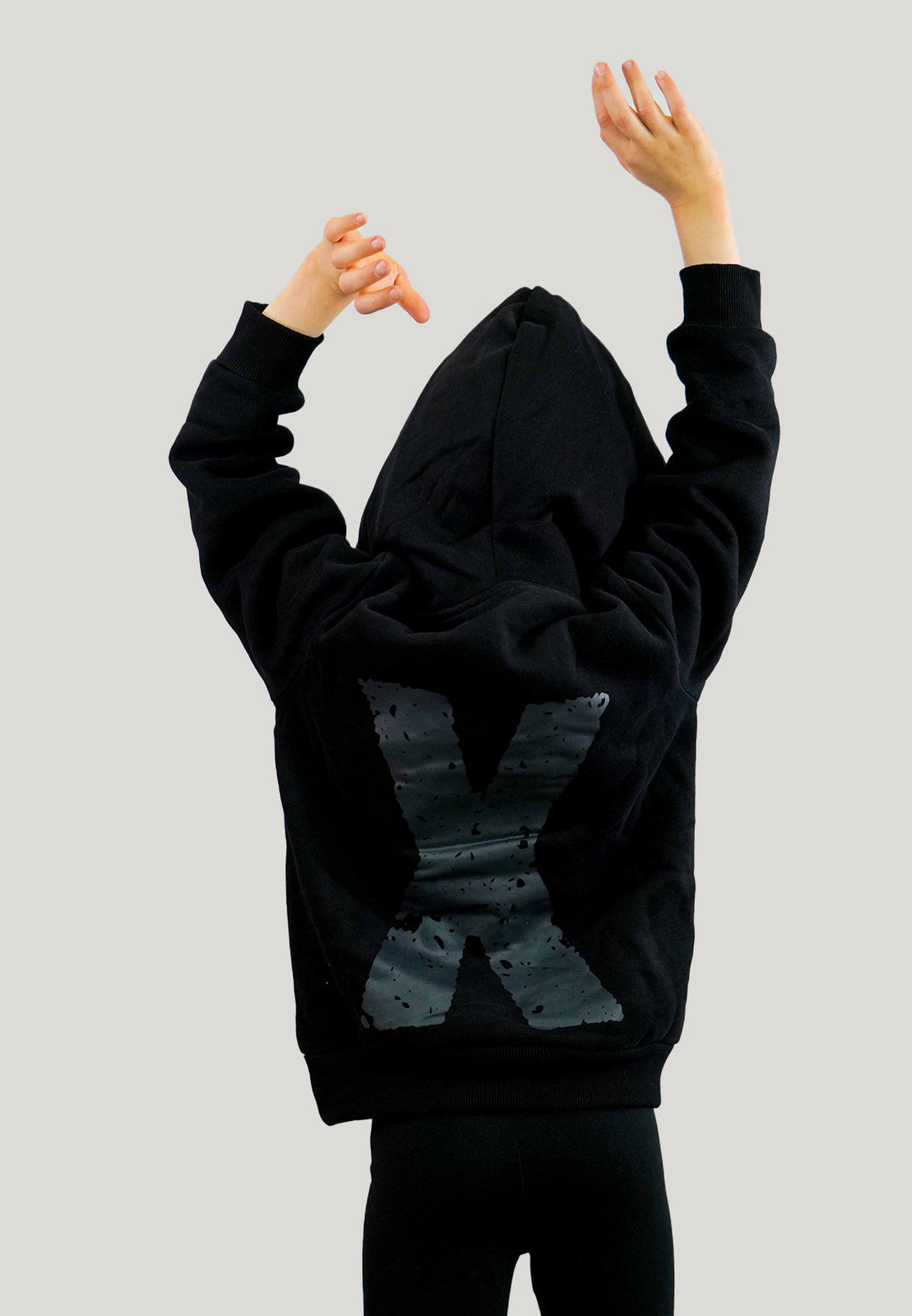 Mädchen von hinten mit XLETIX Kids Hoodie, Kapuze aufgesetzt, Armen oben und großem „X“ am Rücken.