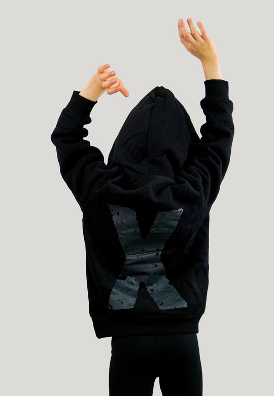 Mädchen von hinten mit XLETIX Kids Hoodie, Kapuze aufgesetzt, Armen oben und großem „X“ am Rücken.