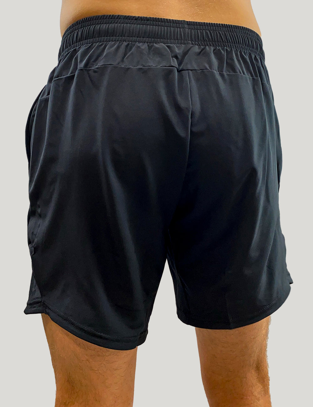 Rückseite eines Mannes im Freien, er trägt die schwarzen XLETIX-Funktionsshorts mit glatter, unbedruckter Rückseite und elastischem Bund.