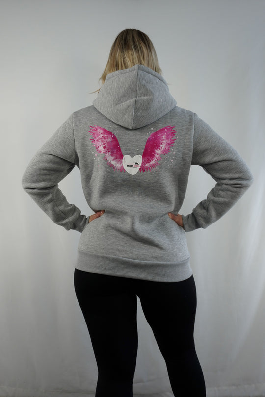 Rückseite einer Frau im grauen Muddy Angel Hoodie mit Flügeln und Herzlogo auf dem Rücken.